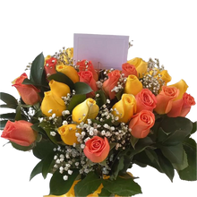 Cargar imagen en el visor de la galería, Arreglo de rosas amarillas y naranjas con flores blancas y follaje verde en jarrón transparente con lazo amarillo